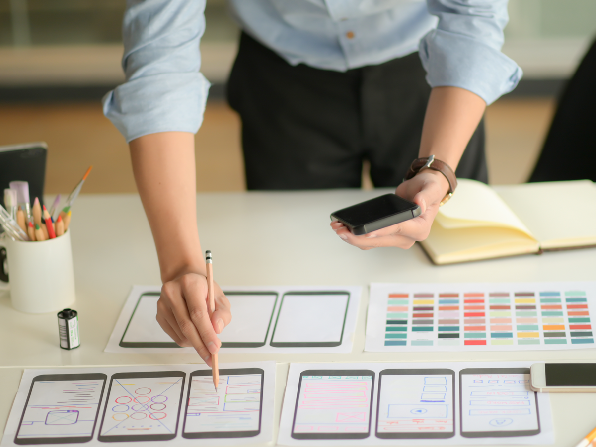 Mesa de trabajo del estudio con bocetos de invitaciones, muestras de color y un celular